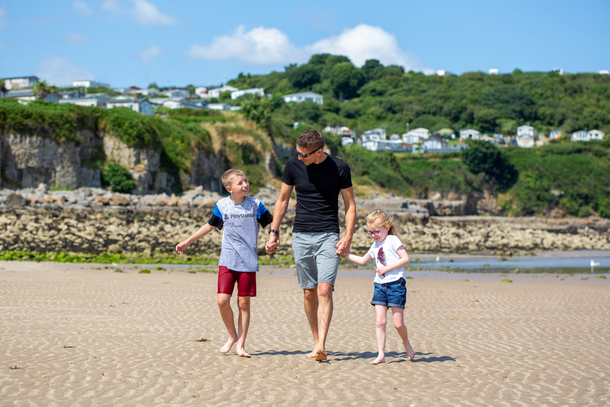 Teulu yn cerdded ar y traeth / Family walking on a beach